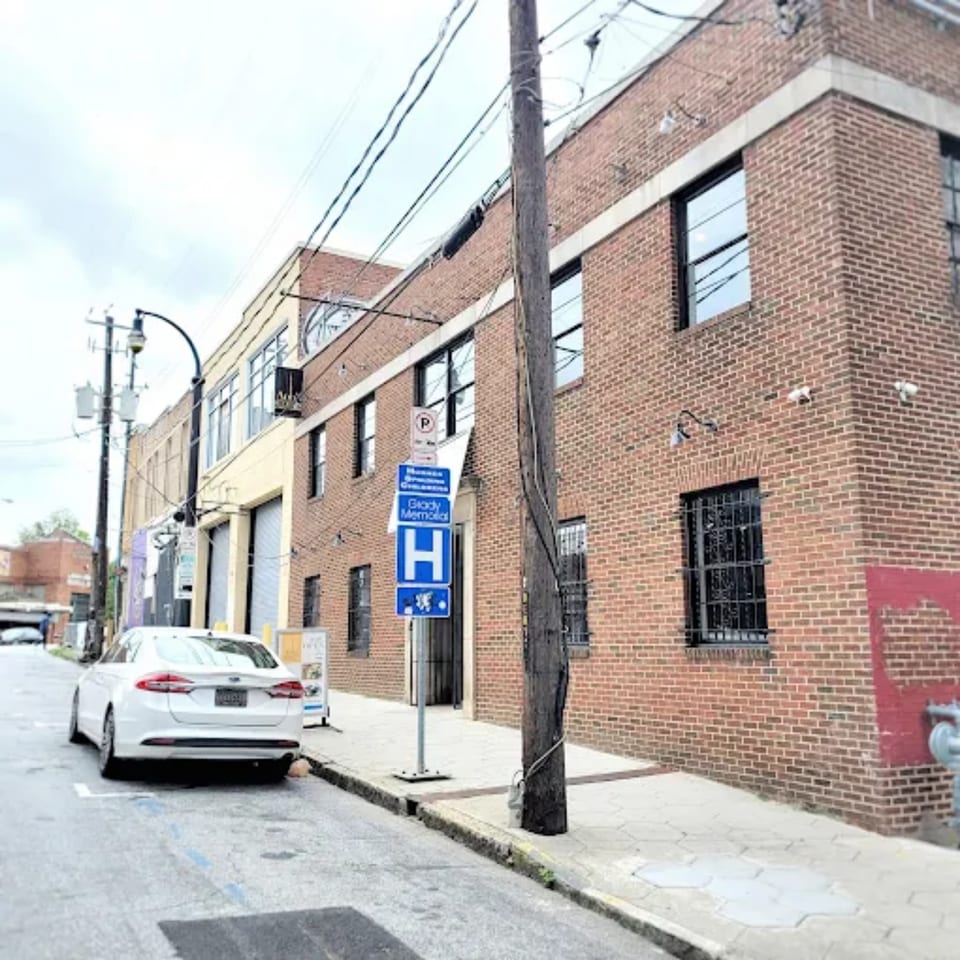 Exterior of Anh's Kitchen, a brick building with a white car parked on the street.