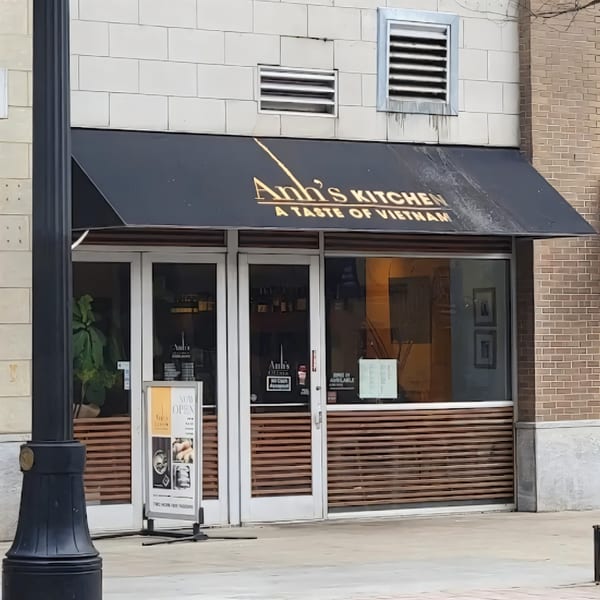 The exterior of Anh's Kitchen, a Vietnamese restaurant, with a black awning and glass doors.