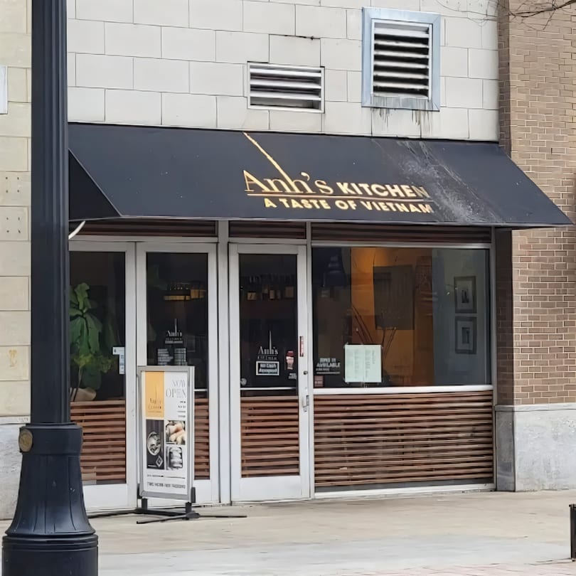 The exterior of Anh's Kitchen, a Vietnamese restaurant, with a black awning and glass doors.